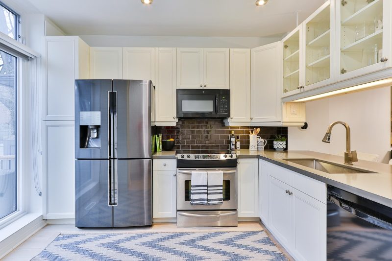 silver french door refrigerator beside white wooden kitchen cabinet